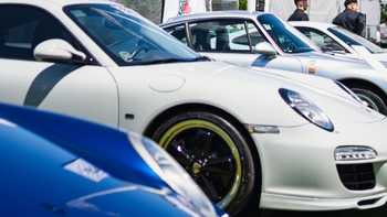 Vista parcial de varios Porsche blancos en exhibición, con un enfoque en los detalles de diseño de los faros y la carrocería.