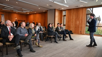 Audiencia atenta escuchando una presentación de Porsche en una moderna sala de conferencias con paneles de madera y ventanas amplias.