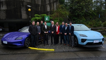 Grupo de hombres y una mujer posando junto a un Porsche Taycan morado y un Porsche Macan eléctrico celeste en una estación de carga en Chile, con un cartel de "Destination Charging".