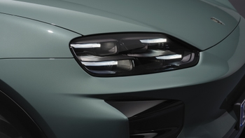 Primer plano del faro delantero derecho y parte del capó de un Porsche Macan eléctrico de color verde en un estudio.