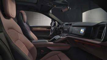 Vista del puesto de conducción de un Porsche Cayenne eléctrico, con pantallas digitales y asientos deportivos en tonos marrones.