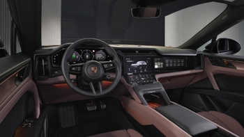 Vista panorámica del interior de un Porsche Cayenne eléctrico, con el volante, las múltiples pantallas digitales y los asientos en tonos marrones.