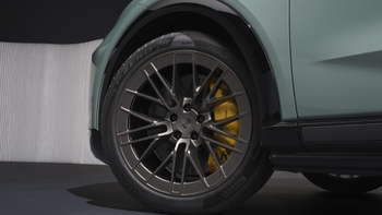 Detalle de la rueda, llanta y freno con pinzas amarillas de un Porsche Cayenne eléctrico de color verde.