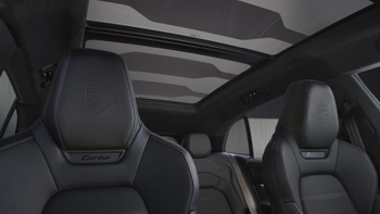 Interior del Porsche Cayenne eléctrico Turbo, mostrando los asientos de cuero negro con el logo y el techo panorámico de cristal.