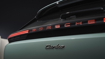 Primer plano del logotipo "PORSCHE" iluminado y la insignia "Turbo" en la parte trasera de un Cayenne eléctrico verde.