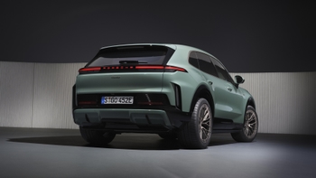 Vista trasera angular de un Porsche Cayenne eléctrico Turbo de color verde estacionado en un estudio con iluminación dramática.
