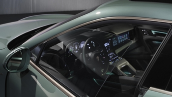 Detalle de la ventanilla delantera abierta de un Porsche Cayenne eléctrico verde, revelando parte del volante y el interior.
