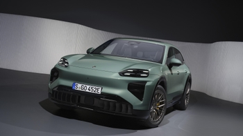 Vista frontal angular de un Porsche Cayenne eléctrico color verde estacionado en un estudio moderno con paredes texturizadas.