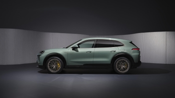 Vista lateral izquierda de un Porsche Cayenne eléctrico color verde estacionado en un estudio con iluminación tenue.