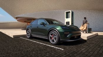 Porsche Macan eléctrico verde estacionado en un punto de carga, con una persona y su maleta, frente a un edificio moderno.