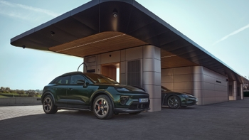 Dos Porsche, un Macan eléctrico y un Taycan, verdes, estacionados bajo una moderna estación de carga con techo oscuro.