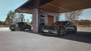 Un Porsche Taycan Cross Turismo y un Macan eléctrico verdes estacionados en una estación de carga con dos puntos.