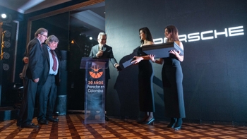 Celebración del 30 aniversario de Porsche en Colombia, con personas en el escenario frente a una pantalla con el logo de Porsche.