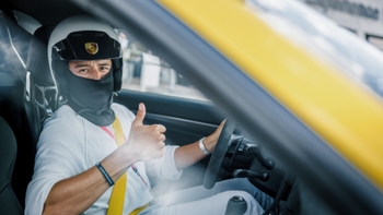 Conductor con casco saludando desde un auto Porsche