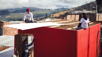Voluntarios de TECHO trabajando en la construcción del techo de una vivienda social en una zona montañosa.