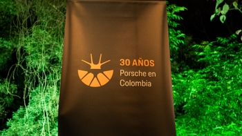 Banner con el logo del aniversario "30 años Porsche en Colombia" contra un fondo de vegetación iluminada.