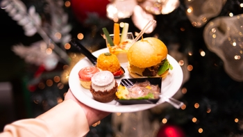 Plato con variados bocadillos gourmet presentados en un evento de Porsche, con decoración navideña de fondo.