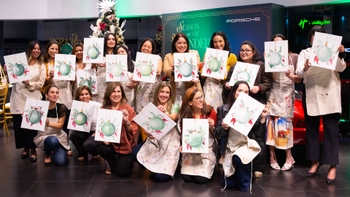 Grupo de mujeres mostrando sus pinturas de adornos navideños en un evento "Season of Wonder" de Porsche.