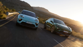 Two sporty compact SUV Porsche Macan driving along the coast together