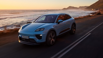 Sporty compact SUV Porsche Macan driving along the coast with sun setting behind