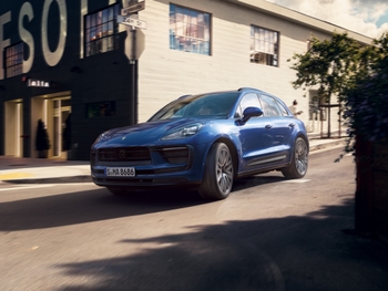 Blue Porsche Macan driving on the road in an urban setting