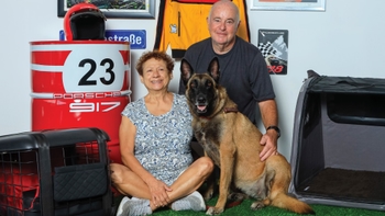 Pareja celebrando con su mascota el Día del Perro en el concesionario Porsche de Cancún