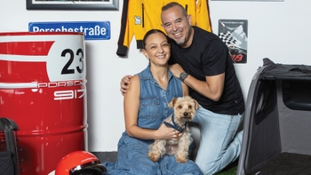 Pareja celebrando el Día del Perro con su mascota en un concesionario Porsche