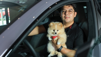 Hombre en un auto Porsche con su mascota
