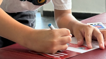 Manos de un niño coloreando un dibujo de un coche Porsche rojo sobre una tarjeta. Actividad de creatividad infantil.