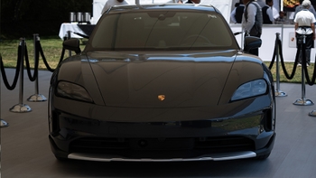 Un Porsche Taycan negro, con su vista frontal destacada, exhibido elegantemente en un evento al aire libre delimitado por cuerdas.