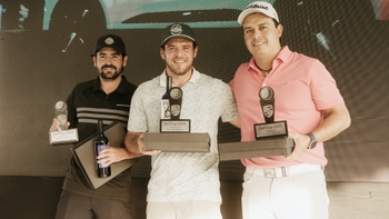 Tres golfistas sonrientes posando con sus trofeos de la Porsche Golf Cup 2025 y una botella de vino.