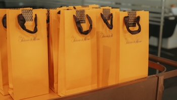 Primer plano de varias bolsas de regalo color amarillo con el logo de "Palacio de Hierro" alineadas en una superficie.