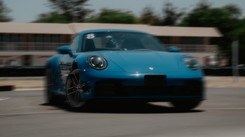 Un Porsche 911 azul, con el número 8 en el parabrisas, en movimiento sobre una pista de carreras, con efecto de desenfoque.