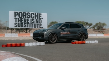 Un Porsche Cayenne Coupe gris en la pista del Porsche Driving Center Mexico, con un cartel "There is no substitute" de fondo.