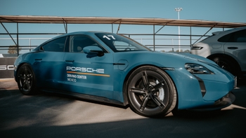 Un Porsche Taycan azul con el logo "Porsche Driving Center Mexico" y el número "17" en el parabrisas, estacionado en una pista o área de evento.