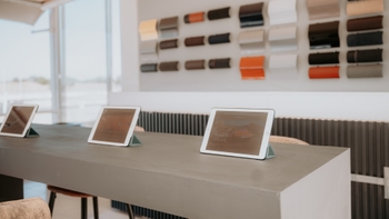 Varias tablets exhiben el Porsche 911 GTS en un showroom de concesionario, con muestras de colores y materiales de fondo.
