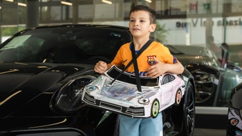 Niño con Porsche de papel en Porsche Centre