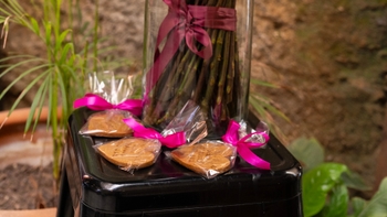 Galletas de regalo con cinta rosa, al lado de un florero.