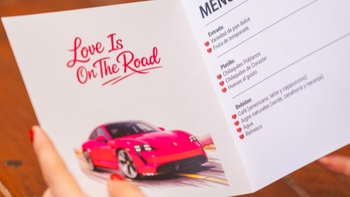 Manos sosteniendo el menu con gráfica de Porsche rosa.