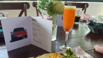 Una mesa servida, con una mimosa y una tarjeta Porsche