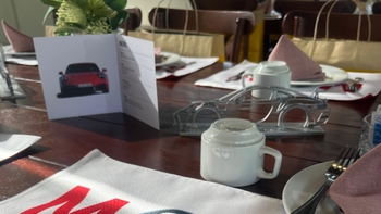 Una mesa servida con una tasa de café y una tarjeta Porsche