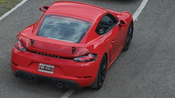 Vista trasera de un Porsche 718 Cayman GT4 rojo en una pista, mostrando su diseño deportivo y placa de Morelos, México.
