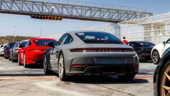 Varios Porsche 911 alineados en el pit lane, vista trasera con el coche gris en primer plano listo para la pista.