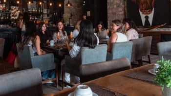 Participantes del Porsche Women Experience Road Tour socializando y disfrutando de bebidas en un ambiente relajado de bar.