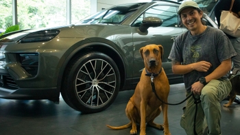 Dueño con su mascota posando al lado de un Porsche en el evento del Día del Perro