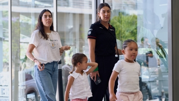 Dos mujeres y dos niñas pequeñas caminan en un evento. Una mujer lleva un polo con el logo de Porsche.