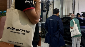 Two pictures: (left) the Porsche electric tote bag being wore by a Porsche technician, (right) Porsche technician and Porsche client holding the tote bag standing in front of a car