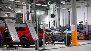 Vista amplia de un taller Porsche con varios modelos, incluyendo un 911 clásico, un 911 GT3 RS y un Macan, en elevadores de servicio.