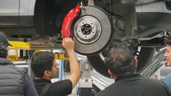 Tecnico de Porsche explica a los clientes sobre el cambio de rines e taller mostrando auto