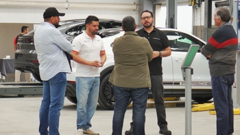 Técnico Porsche y clientes en taller de servicio